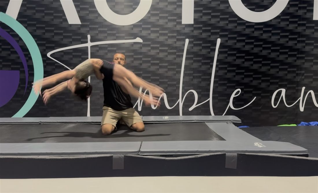 Coach spotting a back flip on the trampoline